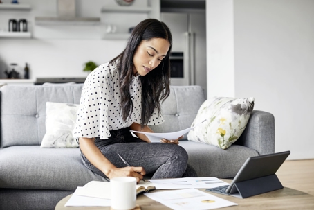 woman sitting on couch analyzing documents