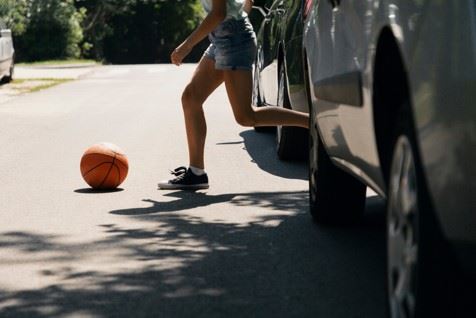 girl chasing a ball into the road in front of cars